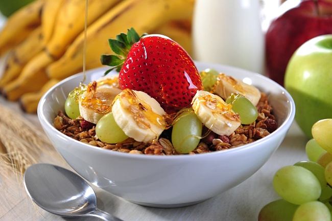 Sebuah mangkok dengan sarapan buah dan sereal.